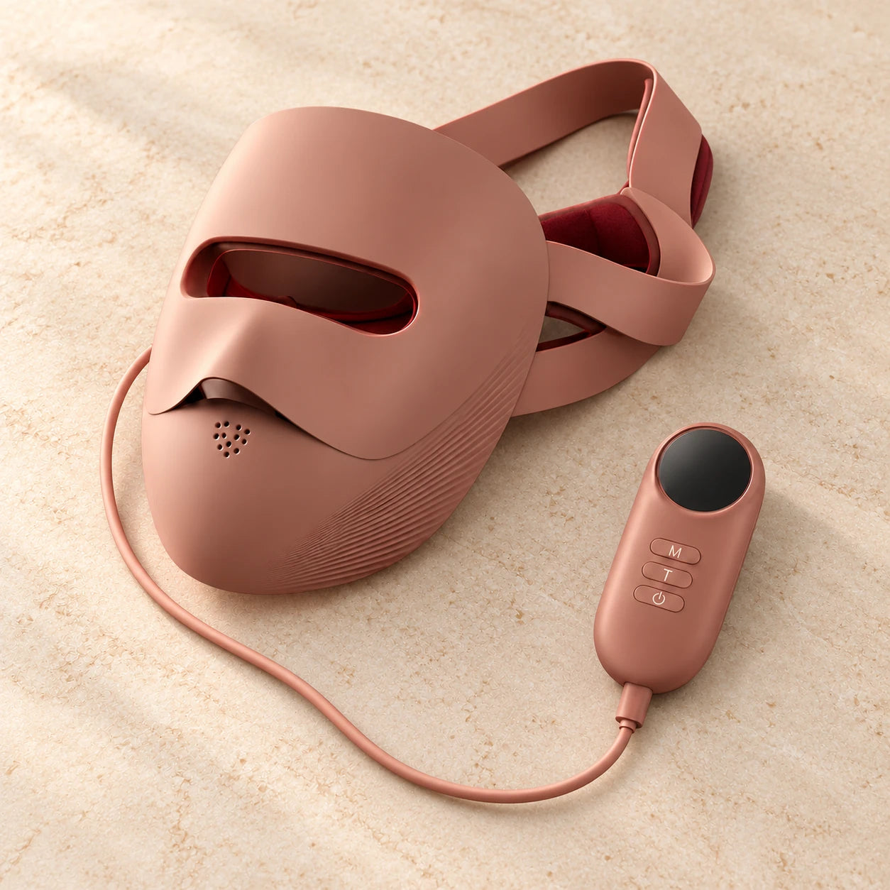 Overhead view of the rose-brown mask, adjustable straps and wired controller